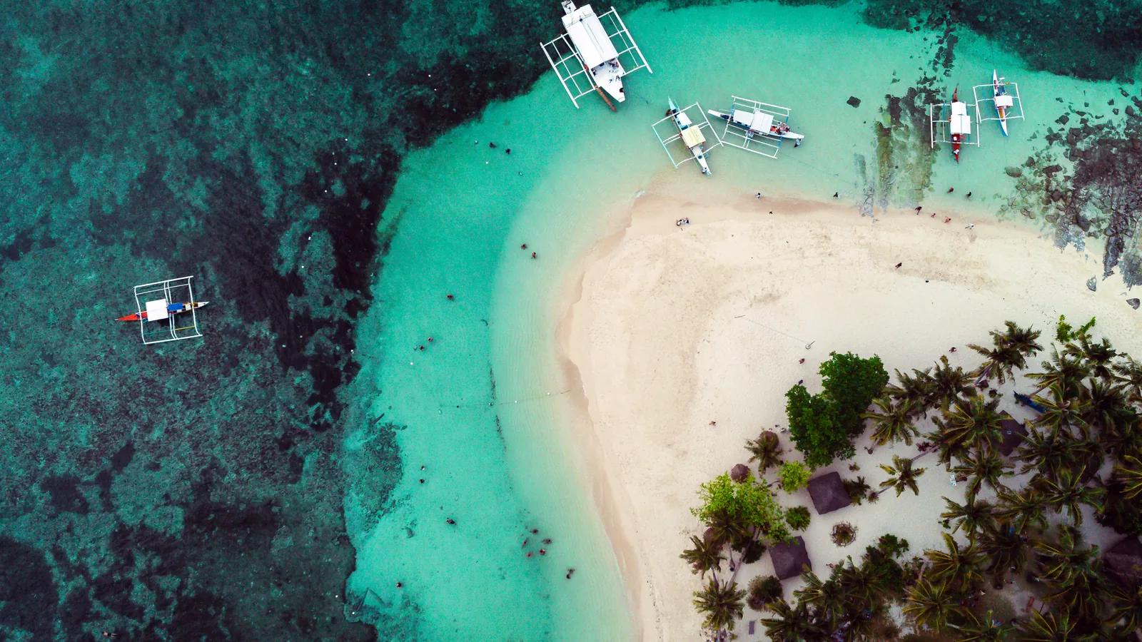 Photo: Michael Angelo Luna (CC BY-SA 4.0) Aerial view of outrigger boats moored off the white-sand beach and palm grove of Guyam Island, Siargao