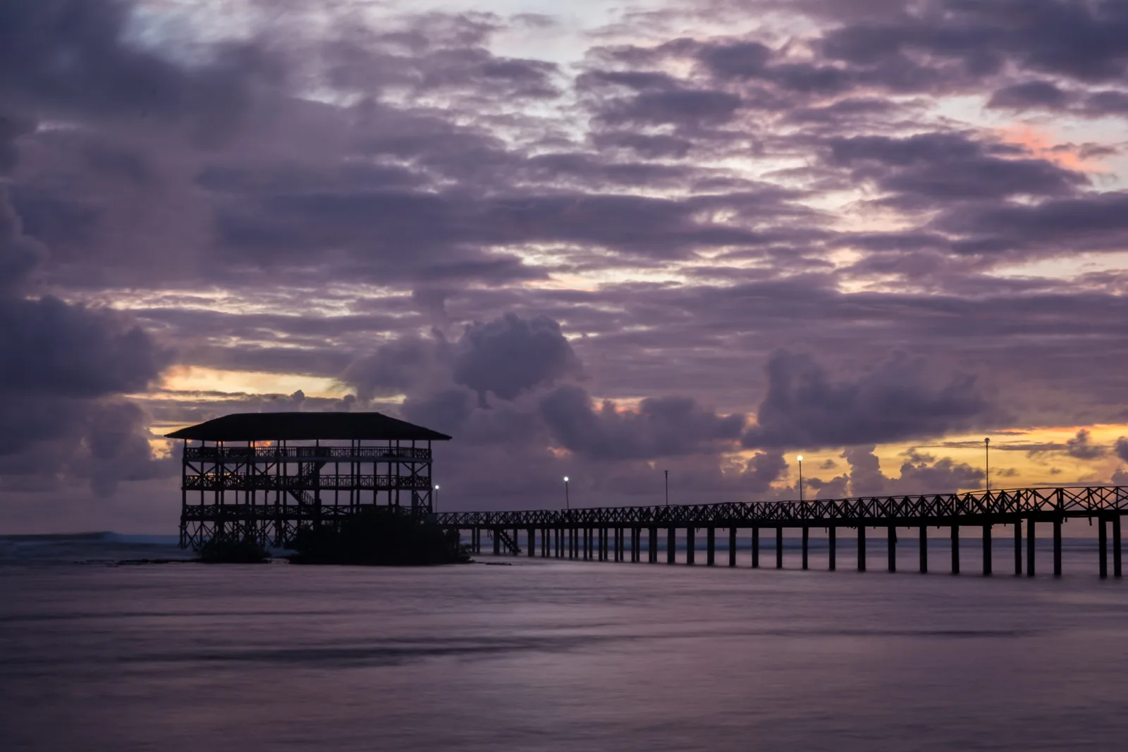 Photo: JupitReyes (CC BY-SA 4.0) The Cloud 9 boardwalk reaching out over the reef at sunrise in General Luna, Siargao, photographed in 2018 when the original three-storey tower still stood