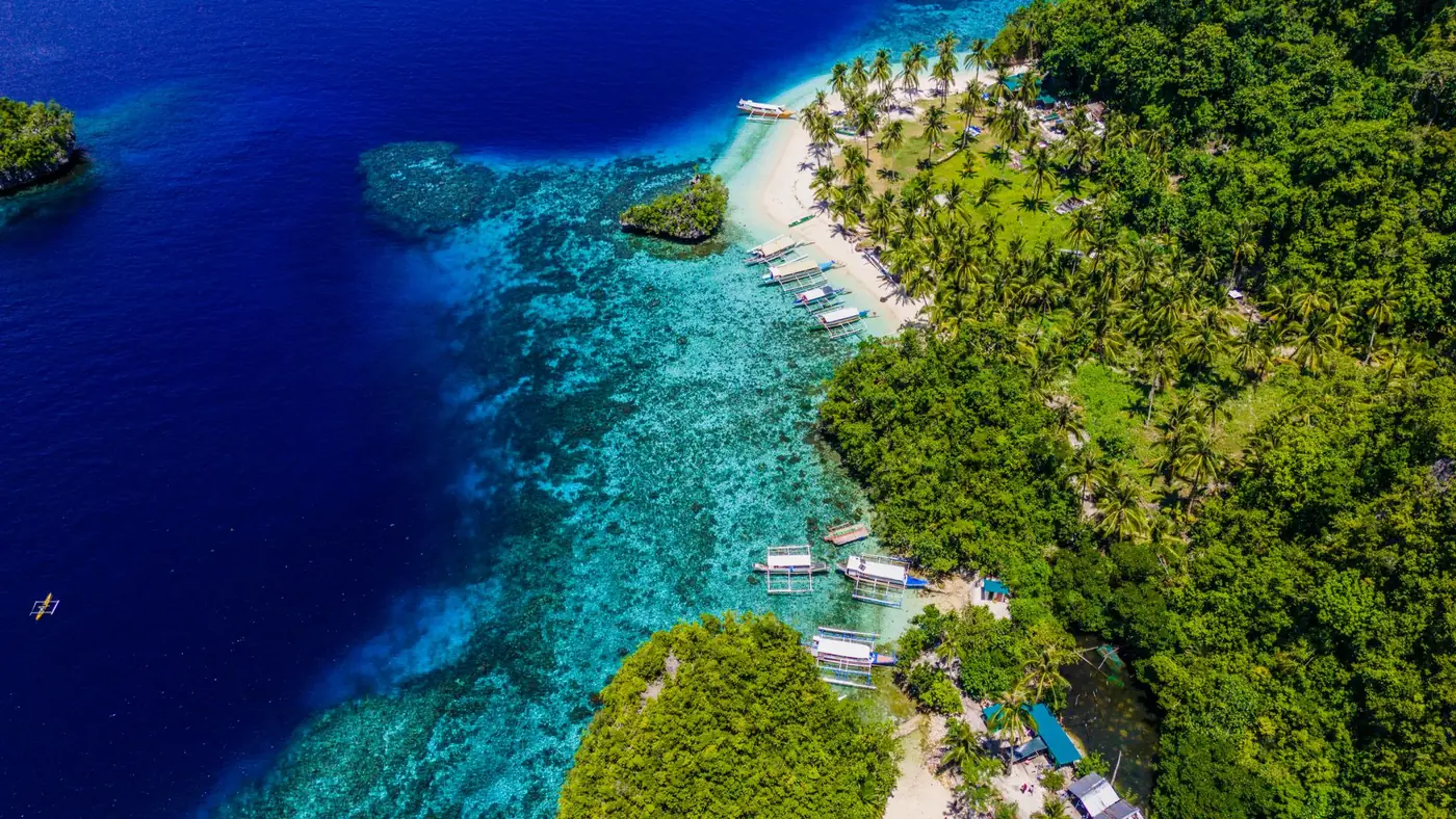 Photo: Ariel Raz (Pexels License) Aerial view of a turquoise bay meeting a densely forested shoreline in Caraga, Philippines