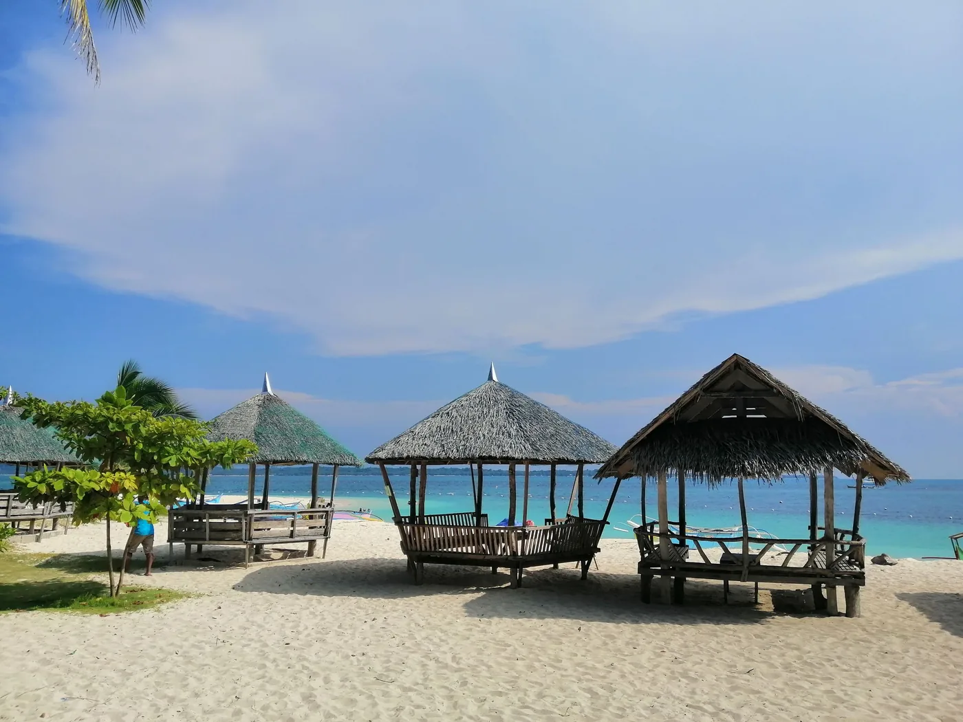 Photo: Chumz Añarol (Pexels License) Timber beach huts under palm trees on the sand at a shorefront in Caraga, Philippines